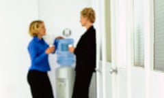 Two women chat around a watercooler