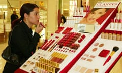 A woman tries on lipstick at the Clarins stand