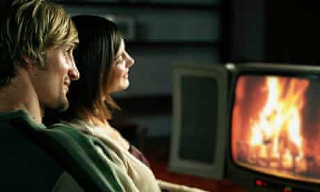 A couple watching a log fire on television
