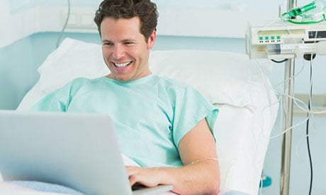 Happy male patient typing on a laptop 