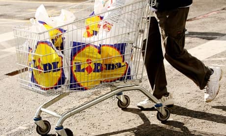 A shopper pushes a trolley with Lidl carrier bags