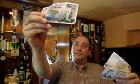A barman holding Scottish pound notes in a pub in London