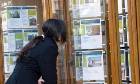 Young woman looking at houses in estate agent window London England UK