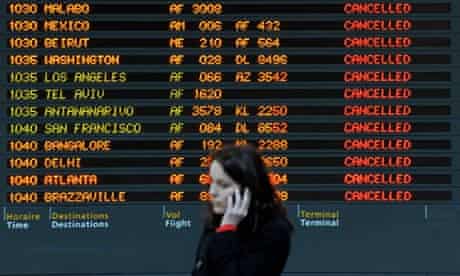 A passenger on her mobile in front of a flight board showing cancellations