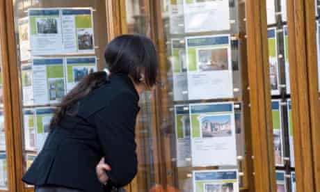 Young woman looking at houses in estate agent window London England UK