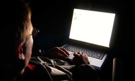 Man in dark night, face lit by blank white LCD laptop display light