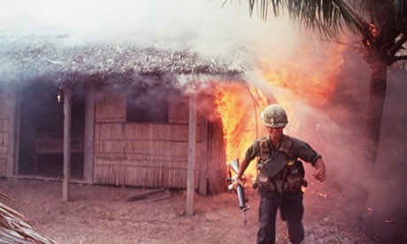A US soldier hurries away after setting fire to a thatched house during the Vietnam War. 