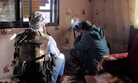 Free Syrian Army fighter points weapon out of house