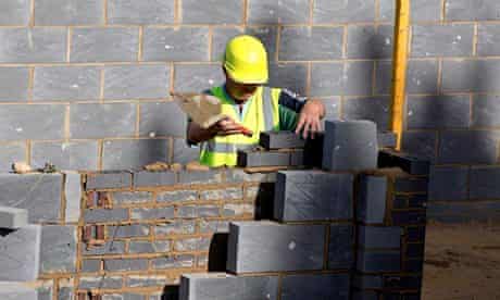 A worker lays bricks at a building site