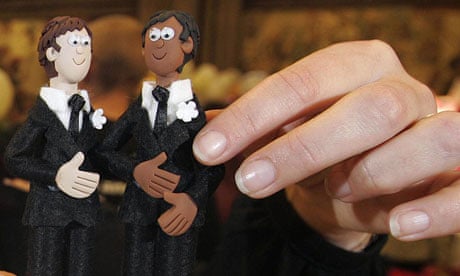 Male wedding-cake figures held by a woman's fingers