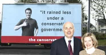 Iain Duncan Smith and his wife pose in front of a spoof election poster