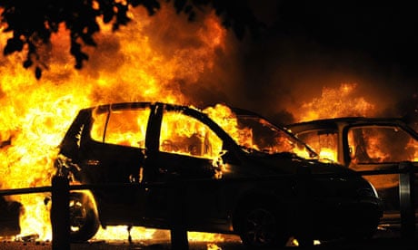 Cars burn on a street in Ealing, as riots spread across London and beyond