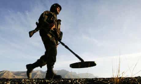 A soldier patrols with a landmine detector