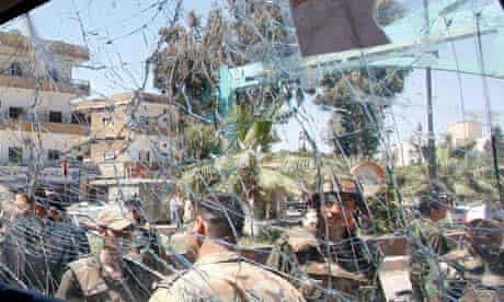 Syrian army soldiers are seen through a damaged military truck window