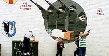 Children play with toy guns under an IRA mural in the mainly-Catholic Market area of south Belfast, Northern Ireland