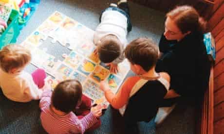 Trainee nursery worker with small children in nursery UK