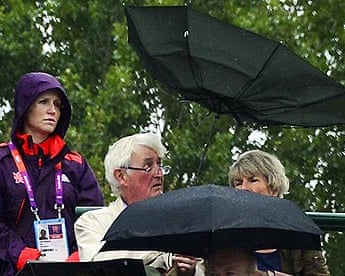 Spectators shelter from rain during the London 2012 Olympics tennis