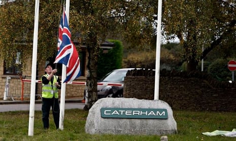 A security guard removes the flags from outside the Caterham F1 team’s factory in Oxfordshire