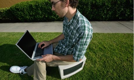 Young man sitting on computer monitor in grass