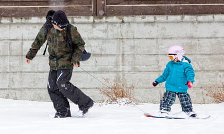 Parent teaching child on snowboard