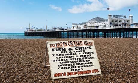A sign advertising fast food on the shingle beach near the pier in Brighton.