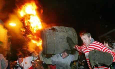 Men carry a burning tar barrel at th Ottery St Mary bonfire night celebrations in Devon