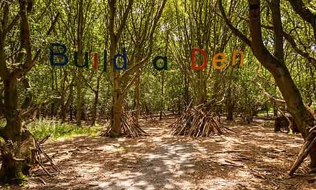 Build a den sign hangs in a sunlit patch of forest