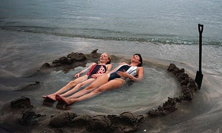 Visitors lie in a home made hot tub at Hot Water Beach in New Zealand
