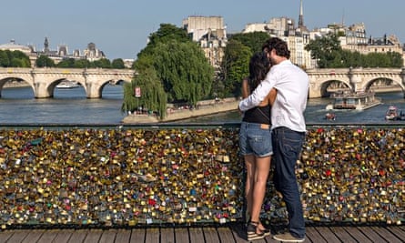 A couple enjoy the view from the Pont des Arts, which is now covered in love locks