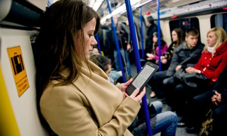 A young woman reads a Kindle on the tube