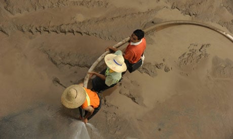Workers clean up mud left by floods on the banks of the Yangtze River, China
