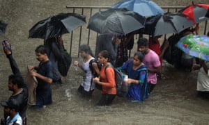 People walk along a flooded street.