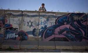 A Palestinian boy looks behind a wall separating the Jewish and Palestinian parts of Hebron in the West Bank. Barack Obama said a lack of progress in peace efforts made a continued US veto at the UN on resolutions condemning Israel more ‘difficult’.