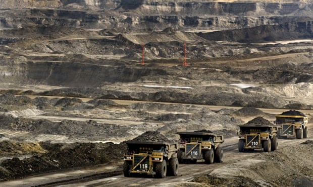 Mining trucks carry loads of oil laden sand at the Albian Sands oils project in Ft. McMurray, Alberta, Canada.