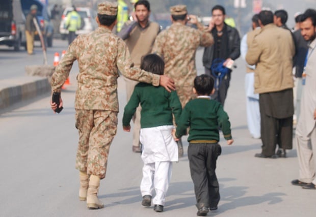 A soldier escorts schoolchildren after they were rescued from the Army Public School which is under attack.