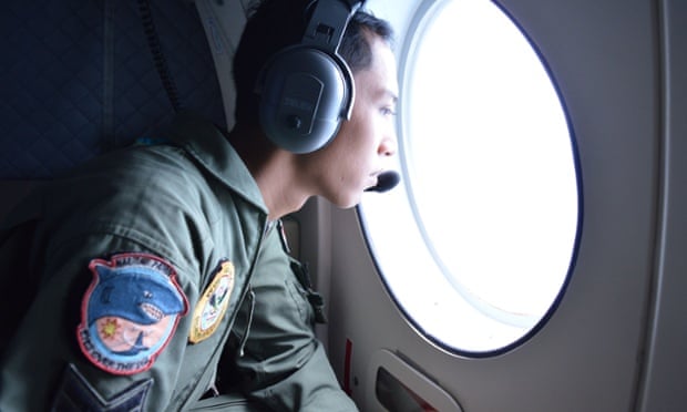 A member of the Indonesian military looks out a window during a search-and-rescue operation for the missing AirAsia flight QZ8501 on Monday.