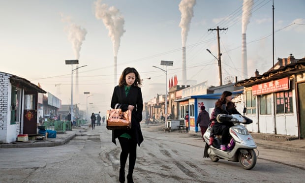 Woman walks through smoke stacks in Shanxi Province, China