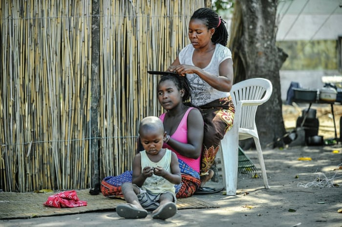 Helia Mulhanga plaits her daughter's hair outside the family home