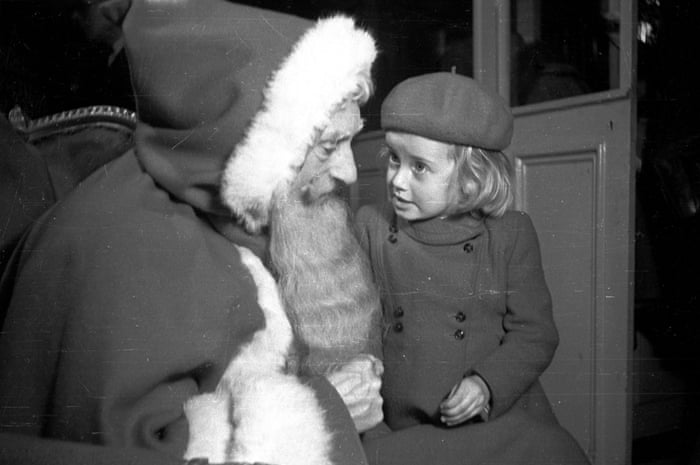 A little girl telling Santa Claus what she would like for Christmas at John Barkers store, London