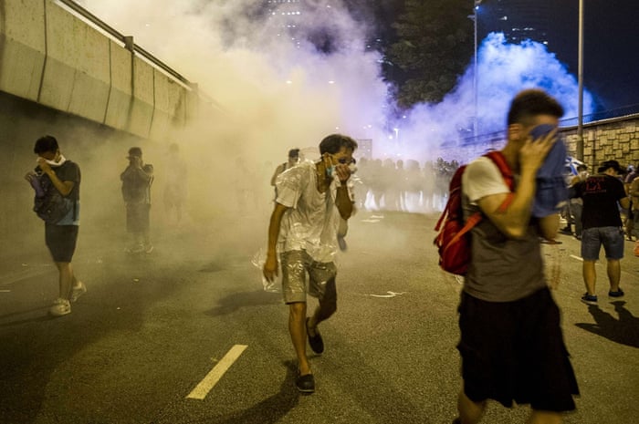 Protesters protect themselves from tear gas fired by police during riots that followed a pro-democracy protest in Hong Kong.