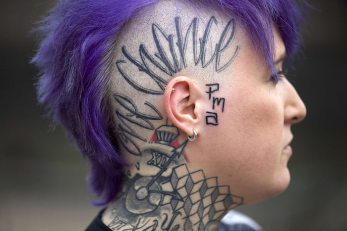 A woman displays a tattoo on the side of her head and neck at the London Tattoo Convention in London